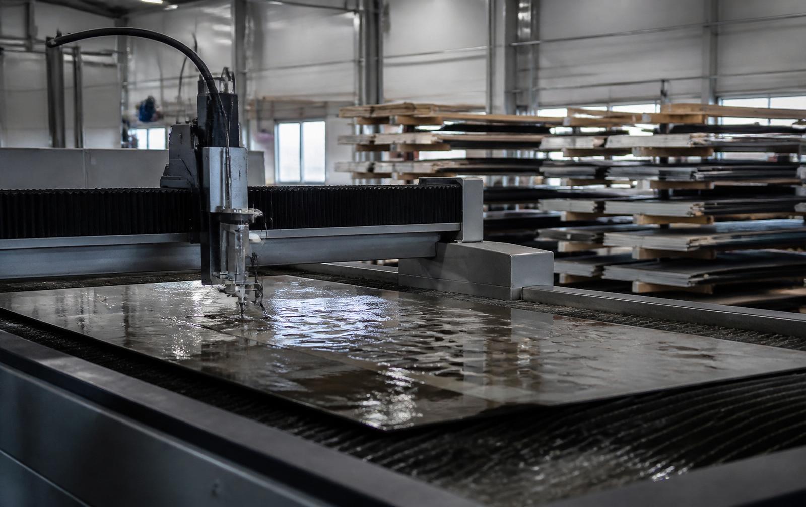 Svensk produktionsmiljö med CNC-styrd vattenskärare och materiallager